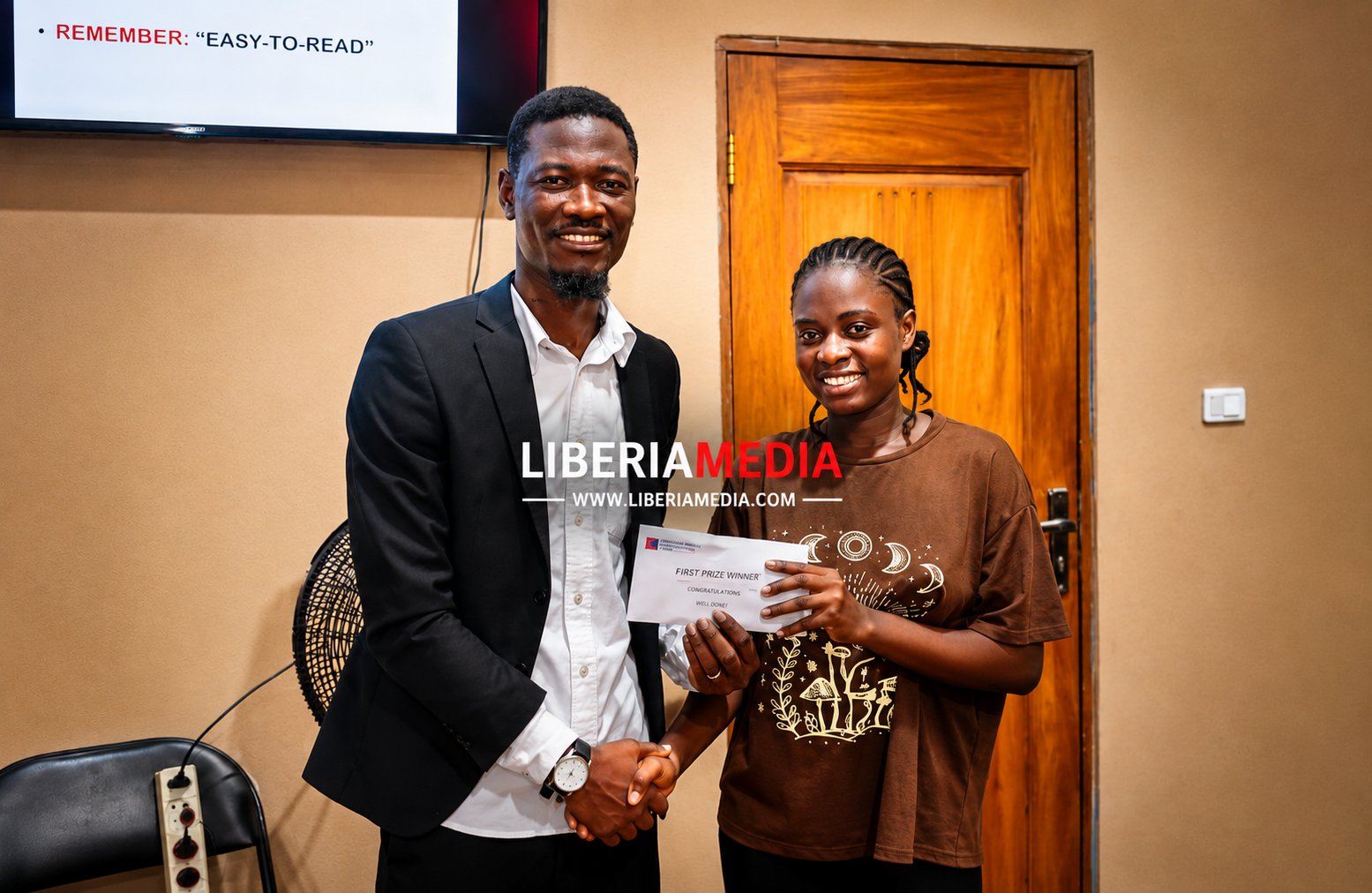 Abdul Karim Sheriff presents prize to first-place winner during Liberia competition award ceremony